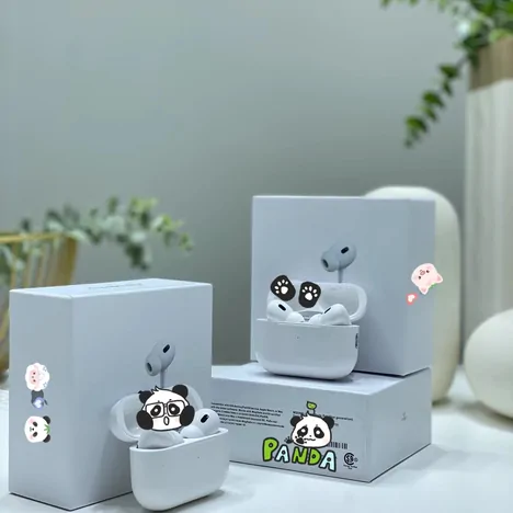 Wireless earbuds in a white charging case with panda stickers, resting on their boxes